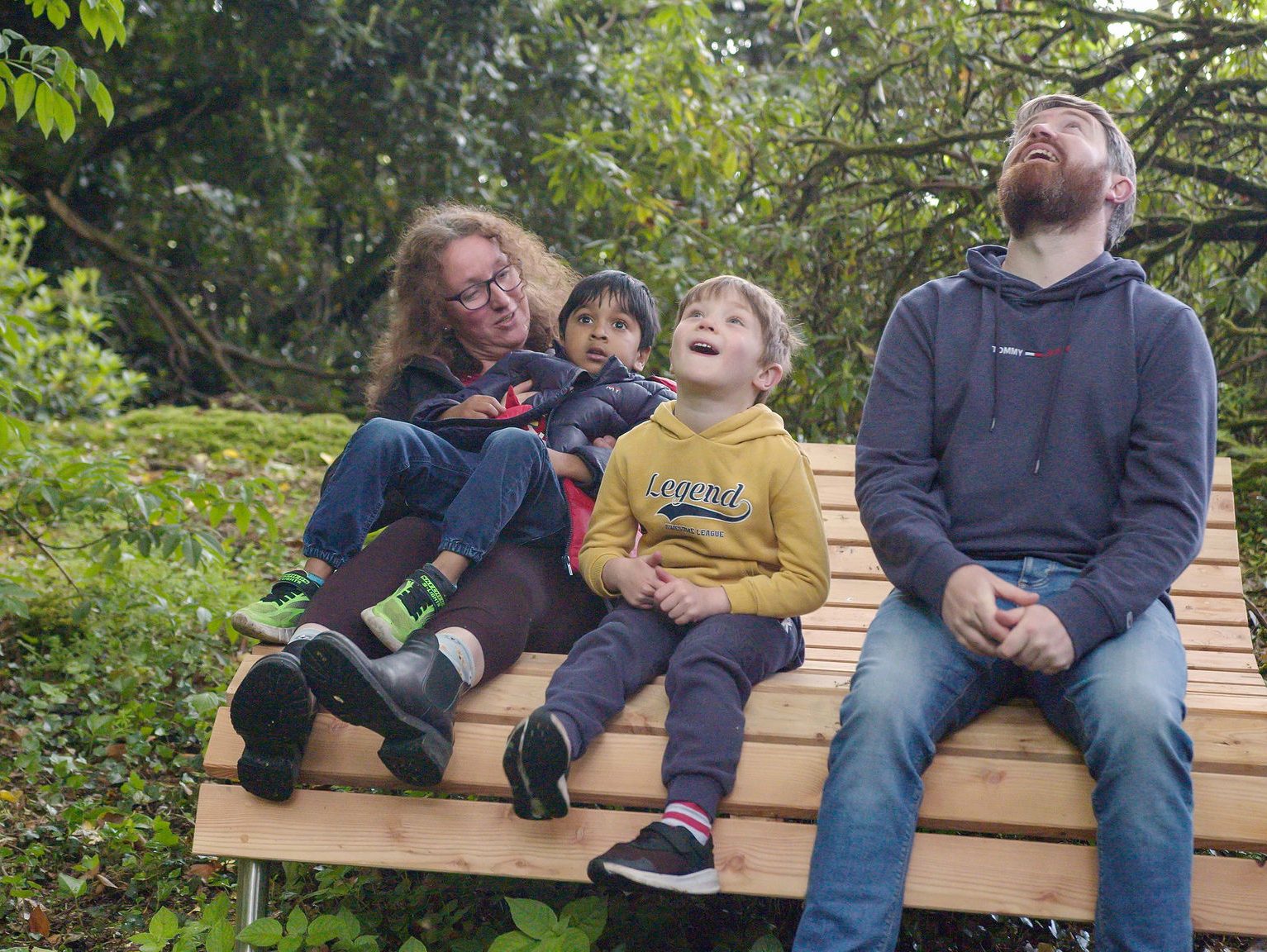 Family of four sitting in a bench admiring the woods