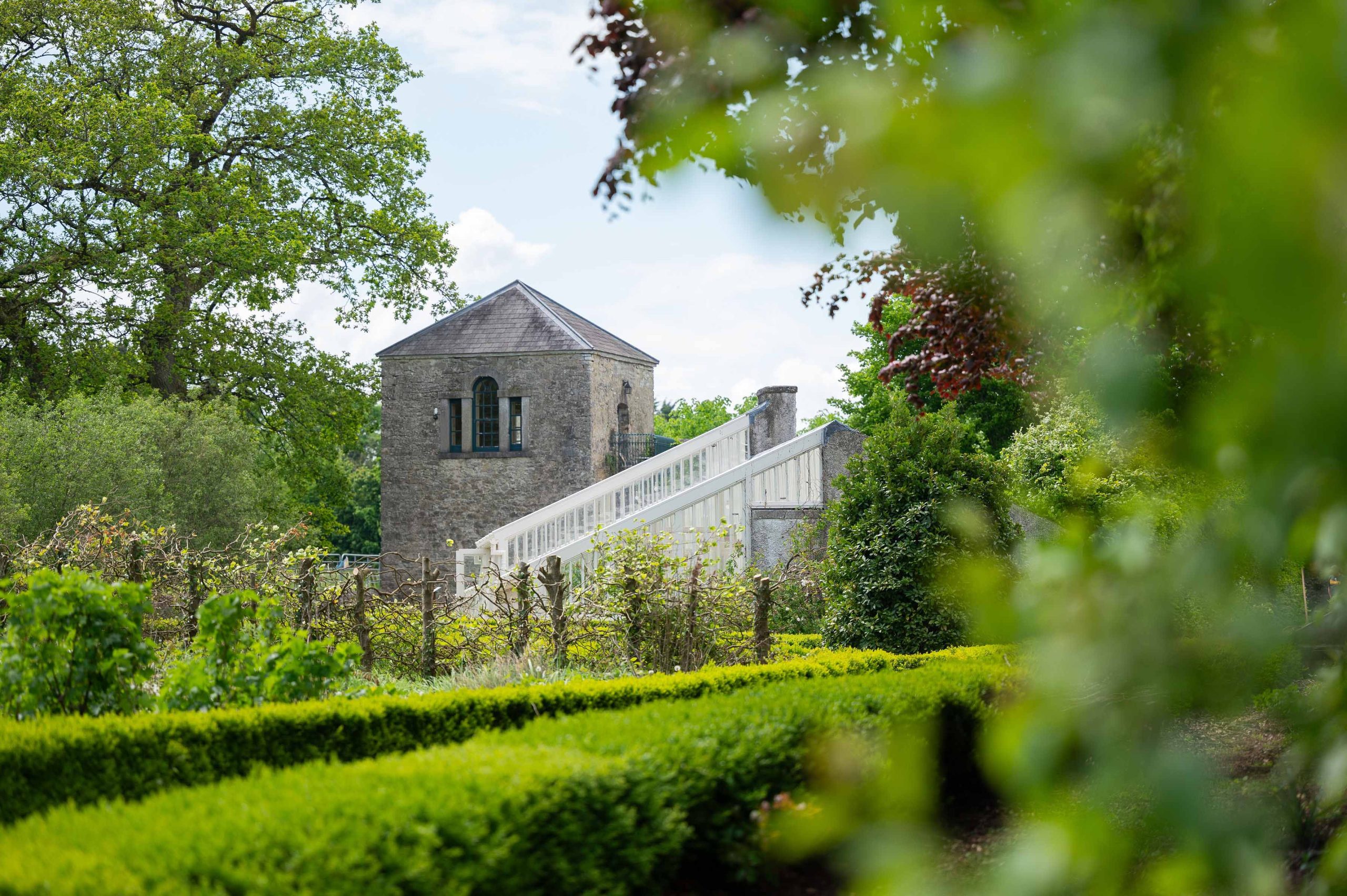 Gardens with historic gazebo tower and glasshouses in the background