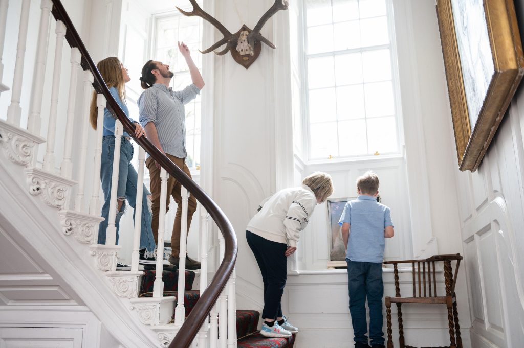 Family of four admiring details around historic staircase of Georgian House
