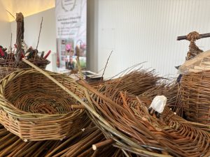 Willow rods, willow baskets and willow basket filled with tools on table