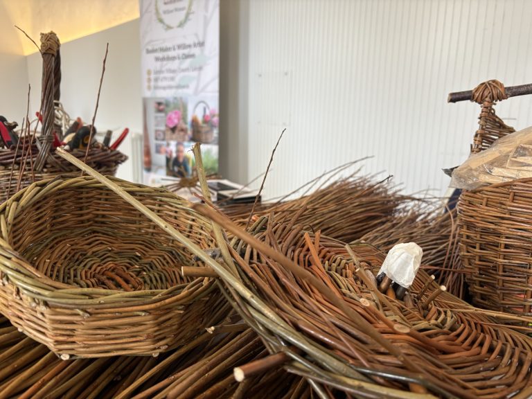 Willow rods, willow baskets and willow basket filled with tools on table